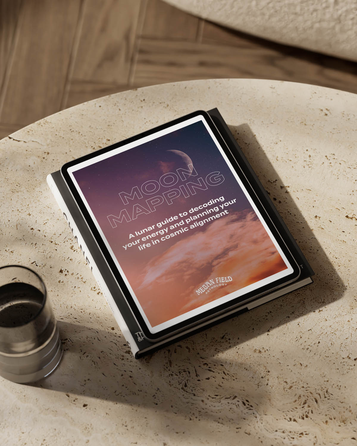 Tablet displaying the Moon Mapping ebook, placed on a textured surface with a glass of water.