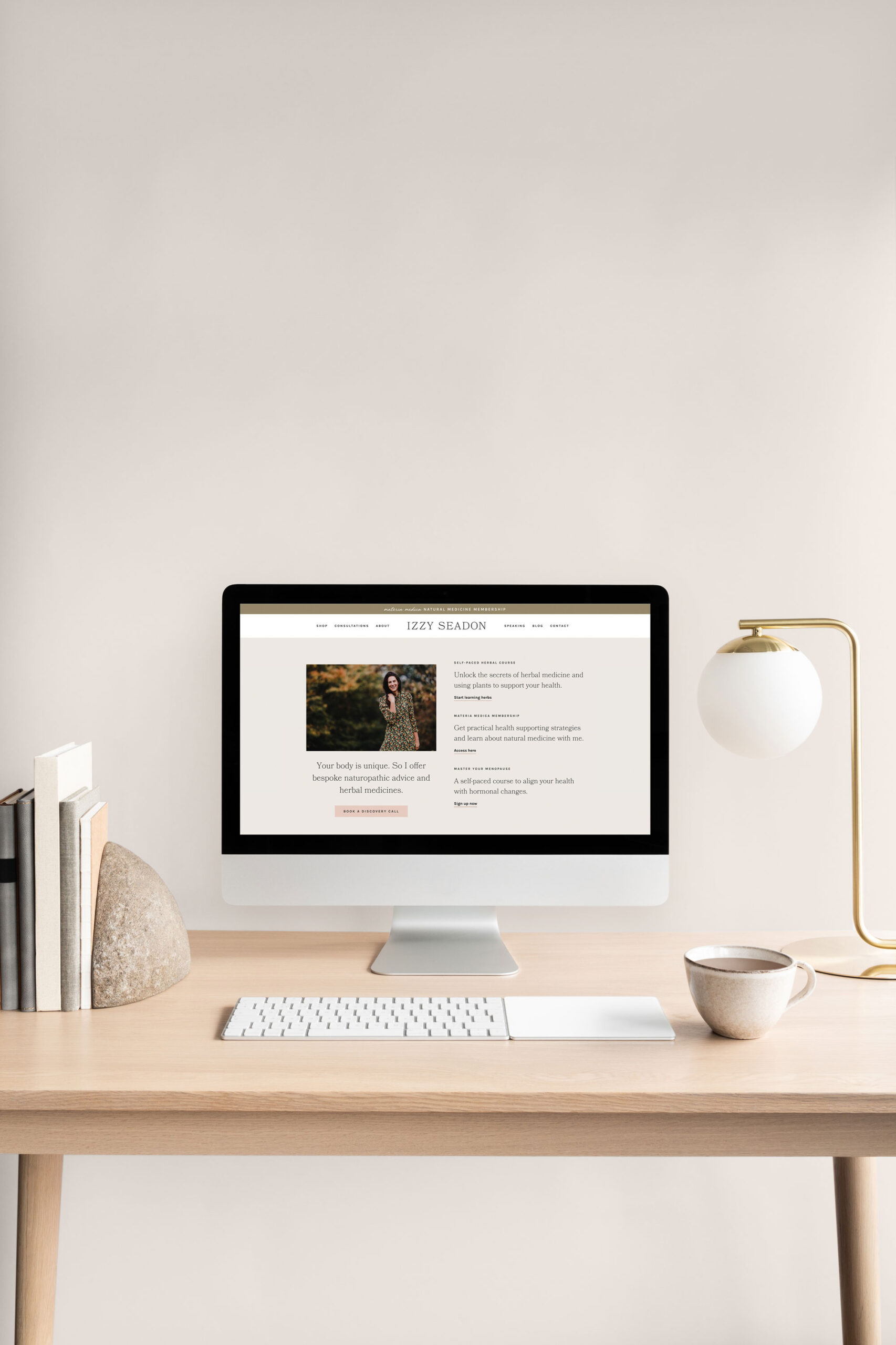 Before you hire a web designer, a desktop computer displaying a custom website design on a minimal workspace.